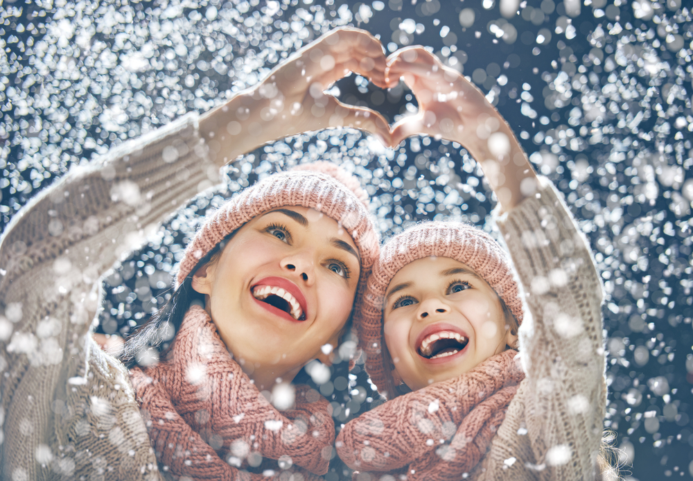 Mom and Daughter in Snow Making Heart with Hands